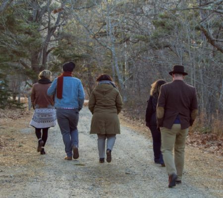 a group of people walking on a path in the woods