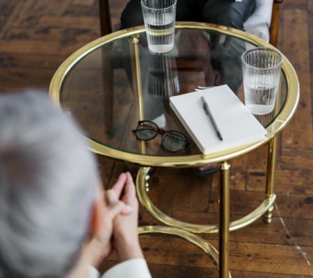 a person sitting at a table with a glass of wine and a phone