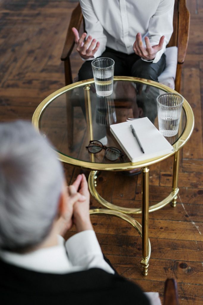 a person sitting at a table with a glass of wine and a phone