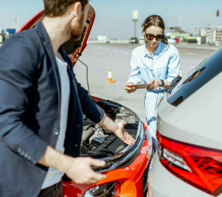 a man and a woman looking at a car engine