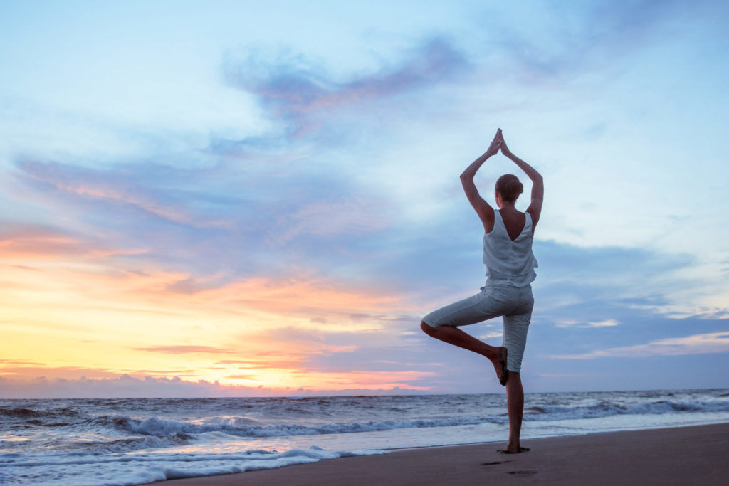 a man doing yoga on a beach