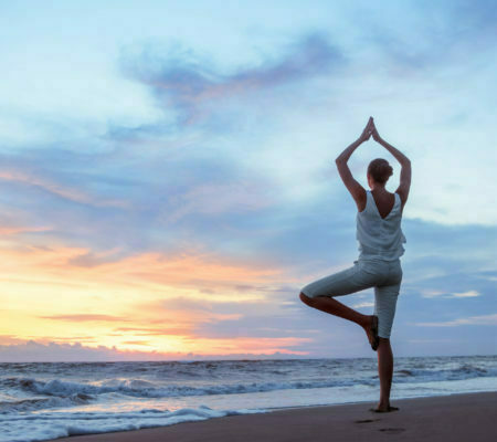 a man doing yoga on a beach