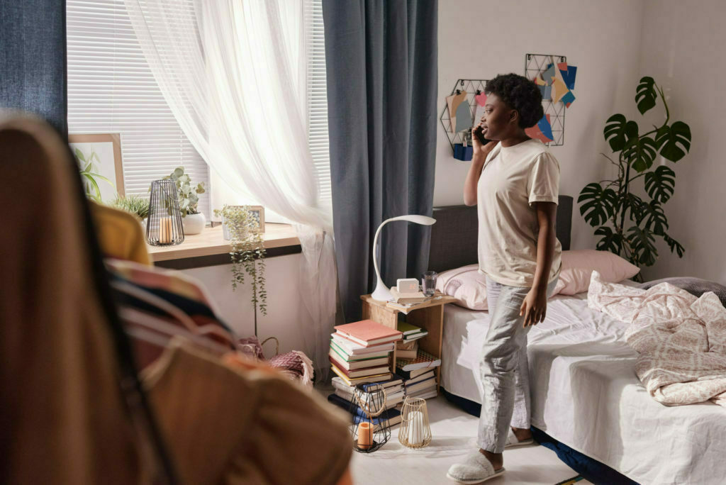 a person standing in a room with a bed and a chair