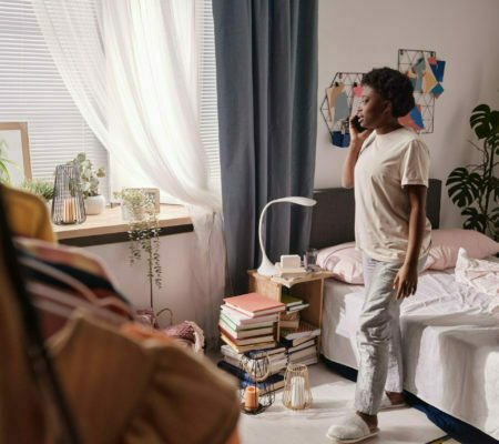 a person standing in a room with a bed and a chair