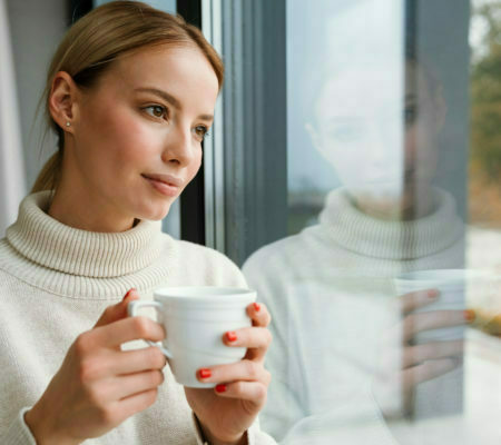 woman-drinking-coffee-while-leaning-on-window-glass