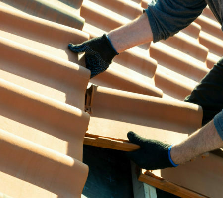 worker-hands-installing-yellow-ceramic-roofing-tiles-mounted-on-wooden-boards-covering