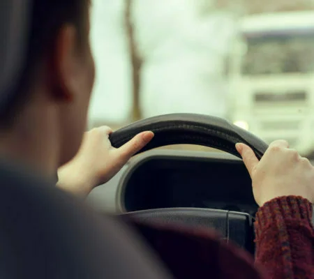 Woman driving car toward a large truck on the road