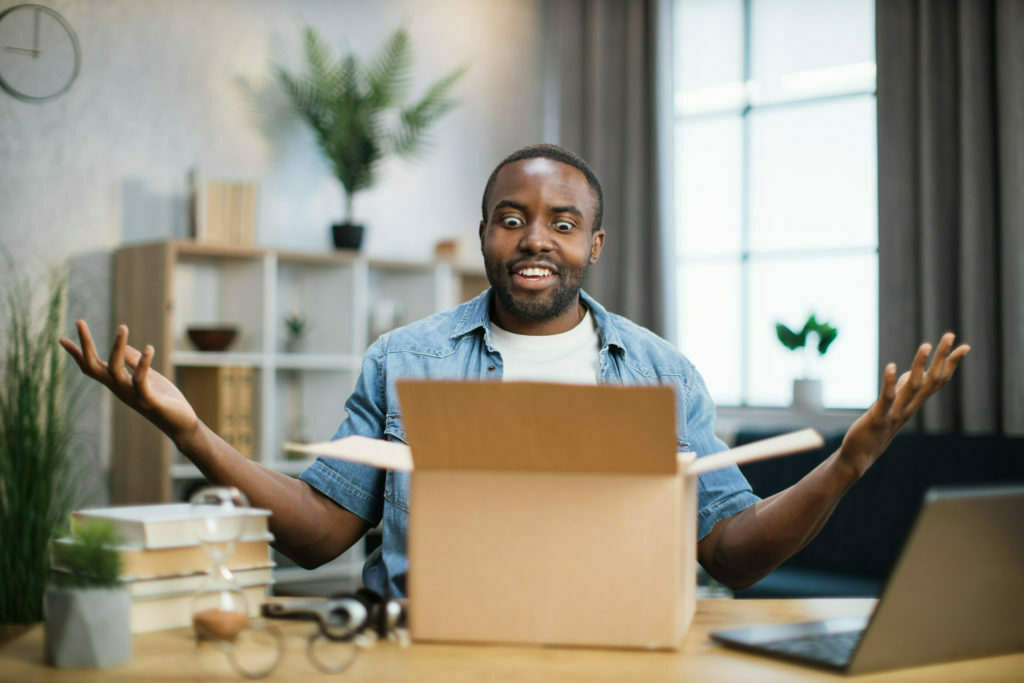 African man sitting at desk and doing unpacking of box