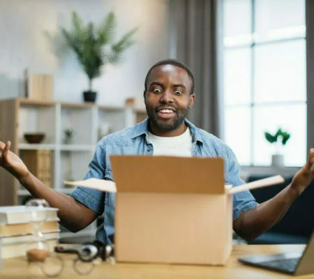 African man sitting at desk and doing unpacking of box